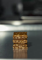 Peanut Oasis energy bars stacked high with creamy peanut butter drizzling over them — all‑natural, high‑protein snack made with dates, oats, and egg whites.